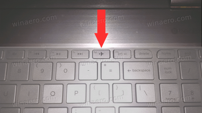 Przycisk trybu samolotowego na klawiaturze laptopa firmy Dell ze strzałką